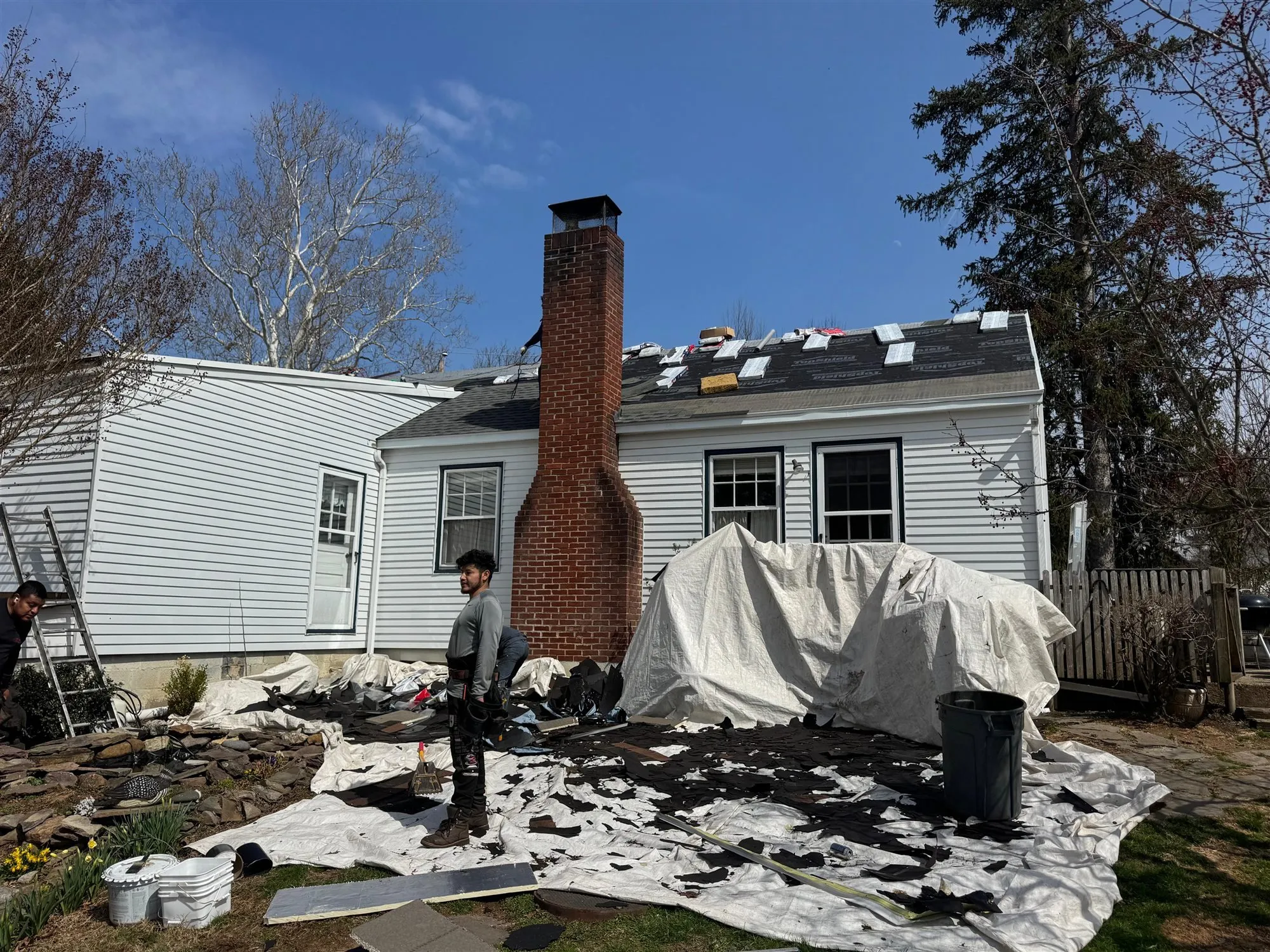Brick chimney on a home during a re-roof, with the yard tarped