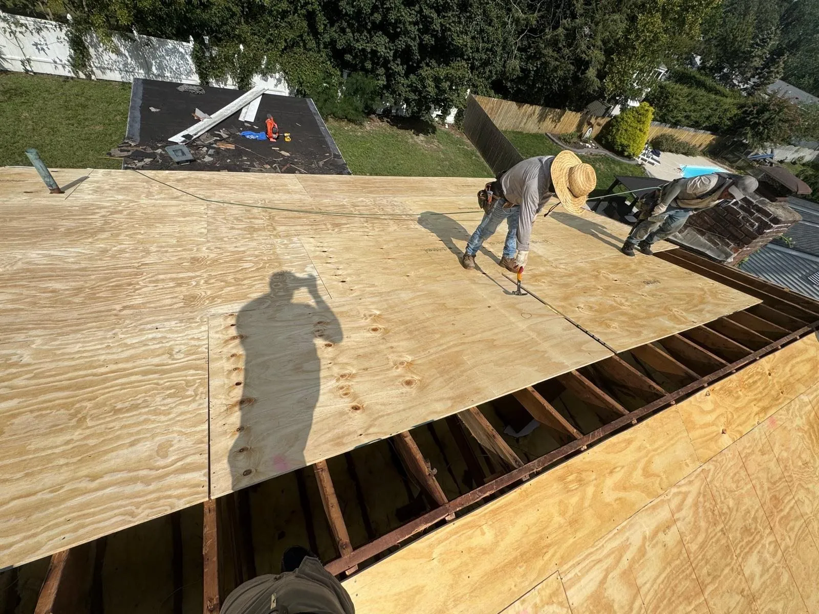Roofer fastening new plywood sheathing on a roof