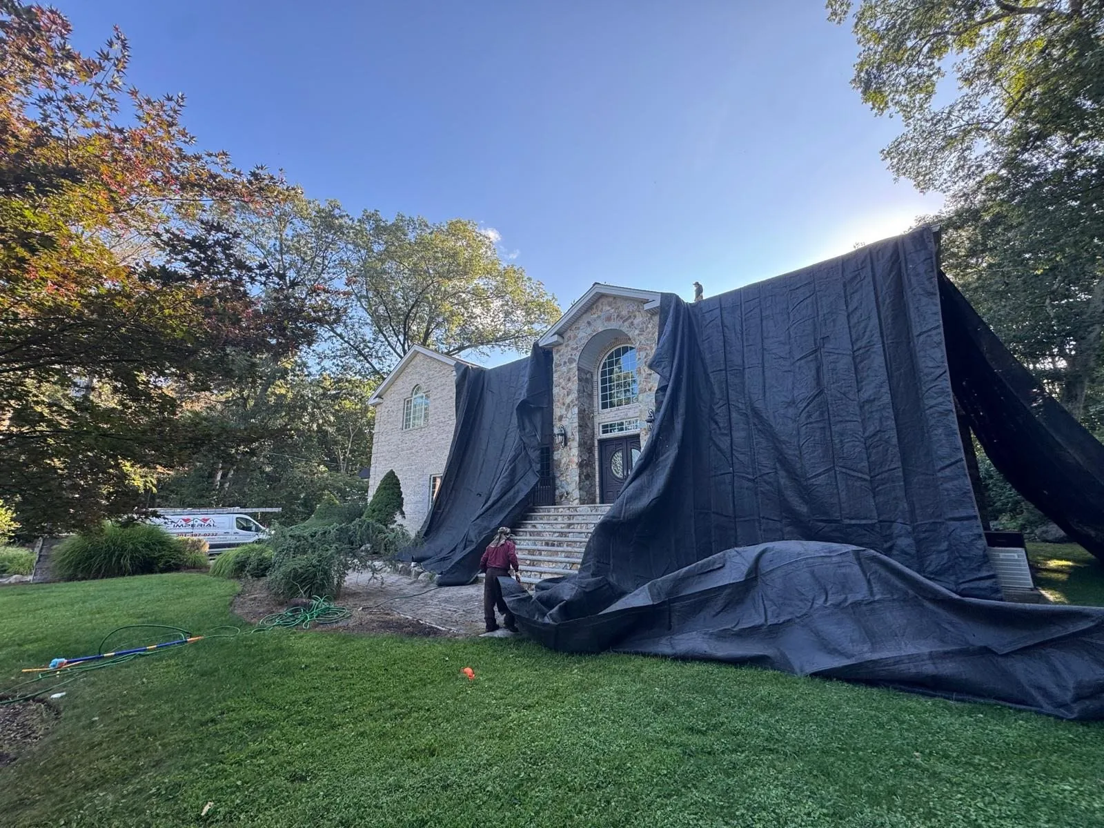 Tarps draped over the front of a stone house during roof work