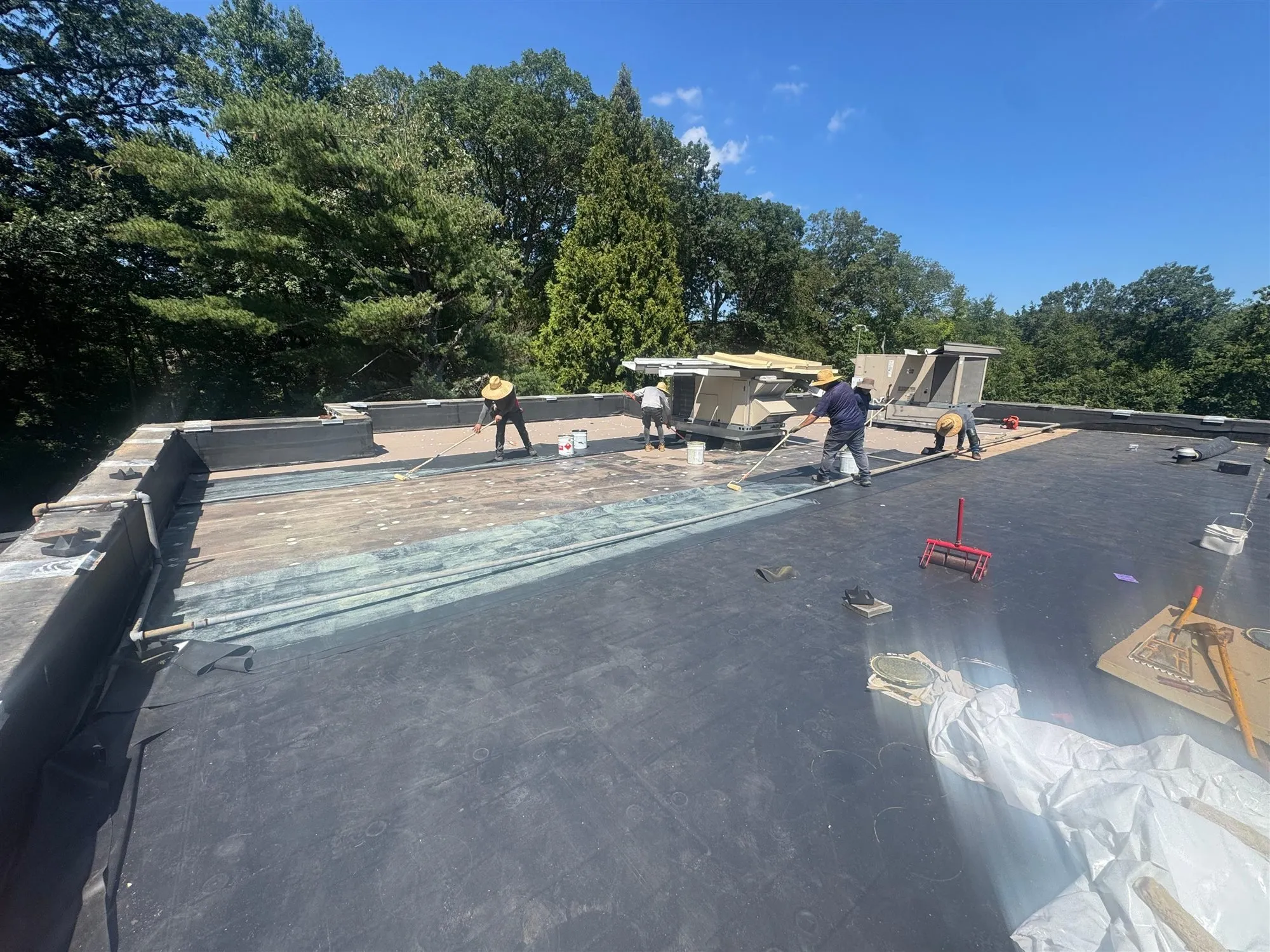 Roofers working on a large flat commercial roof