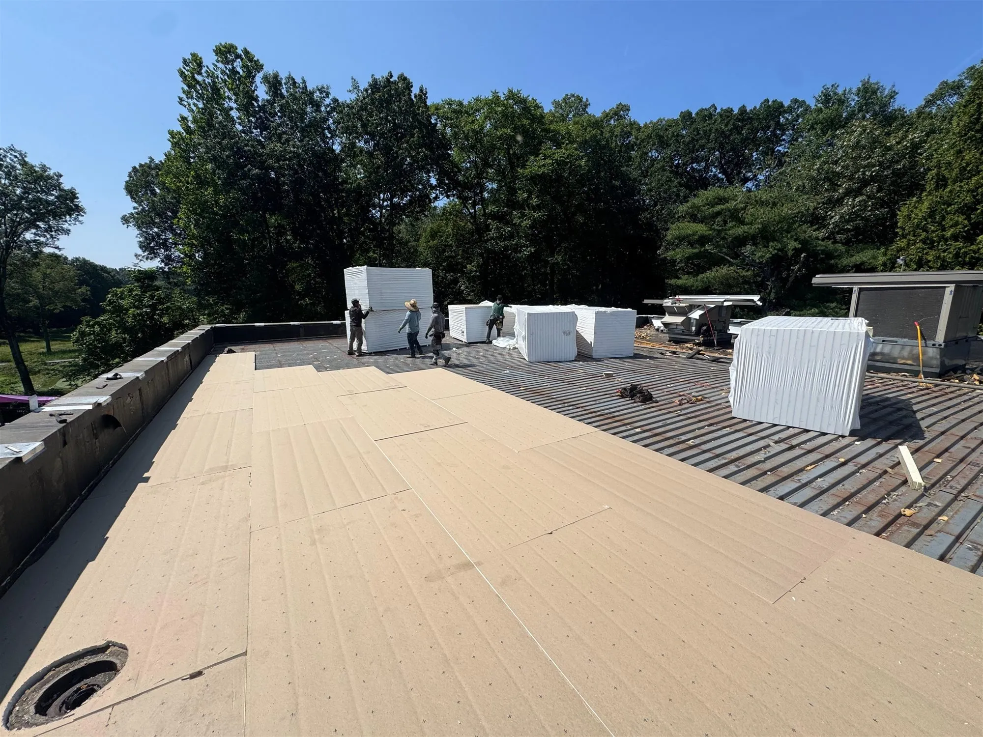 Crew installing a flat roof with insulation boards staged on the deck