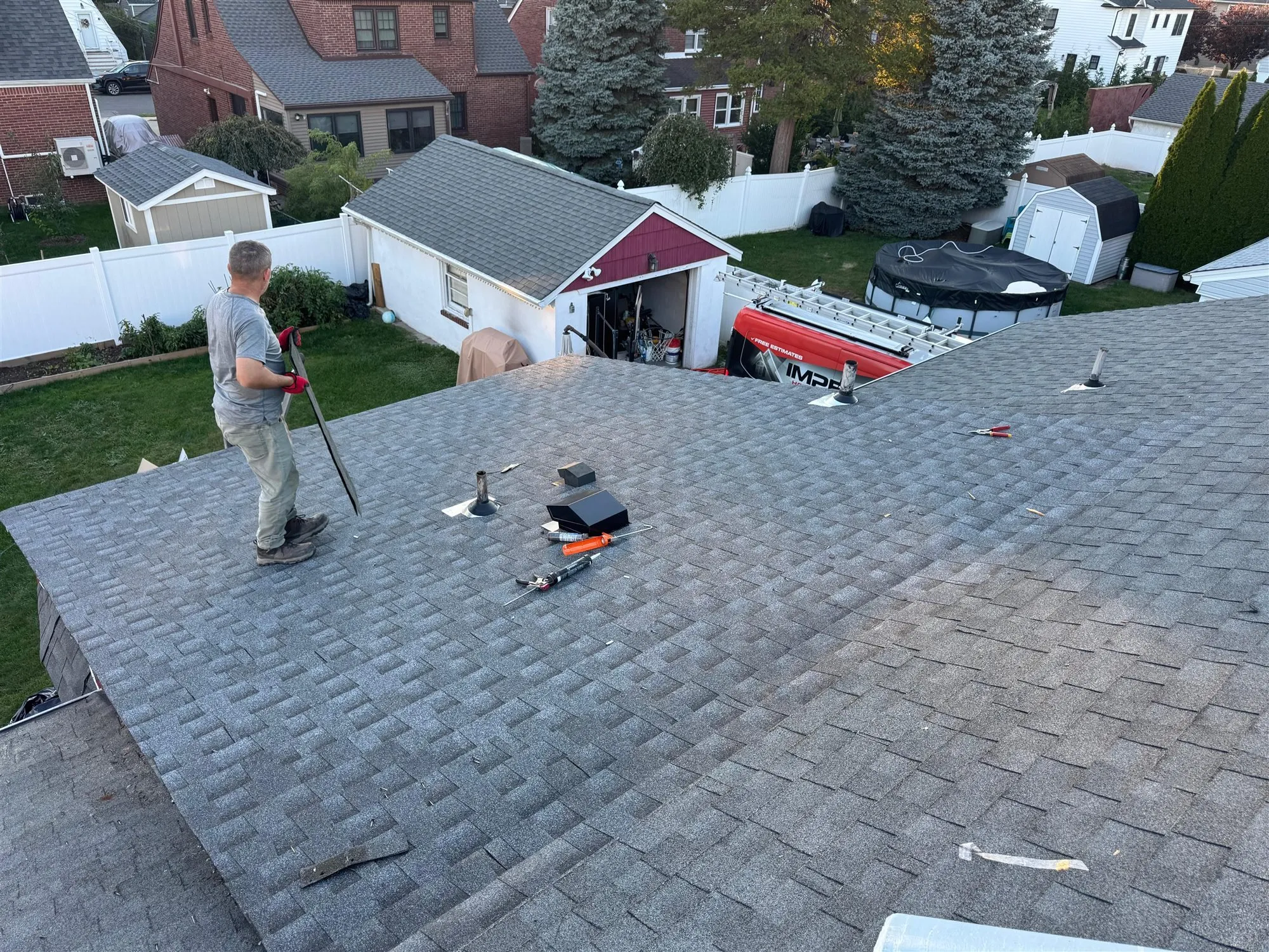 Roofer repairing shingles around a roof vent