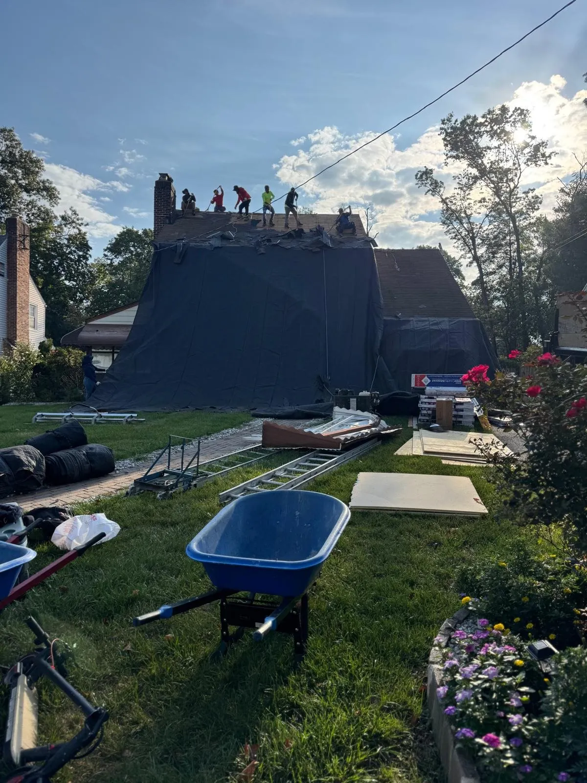 House wrapped in tarps with the crew working on the roof during a tear-off