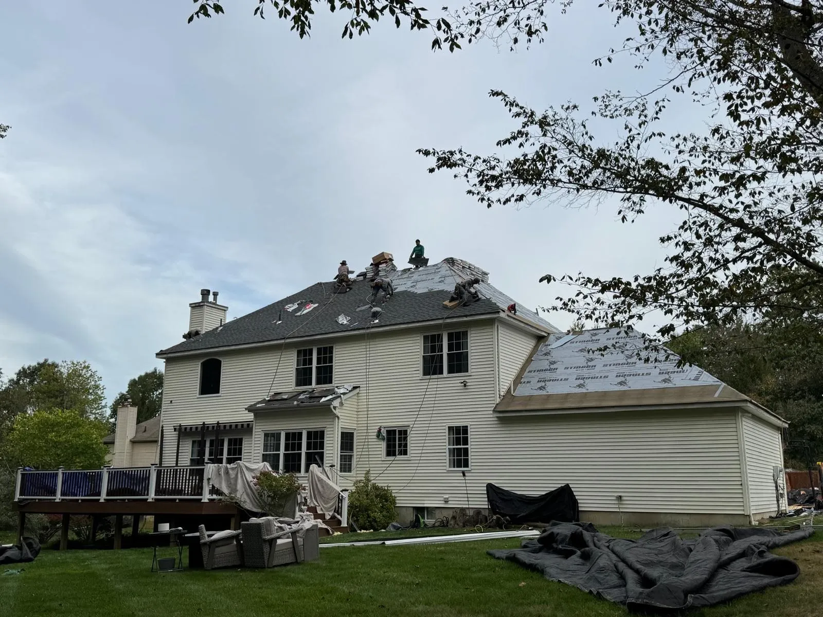 Crew tearing off and re-shingling a two-story colonial