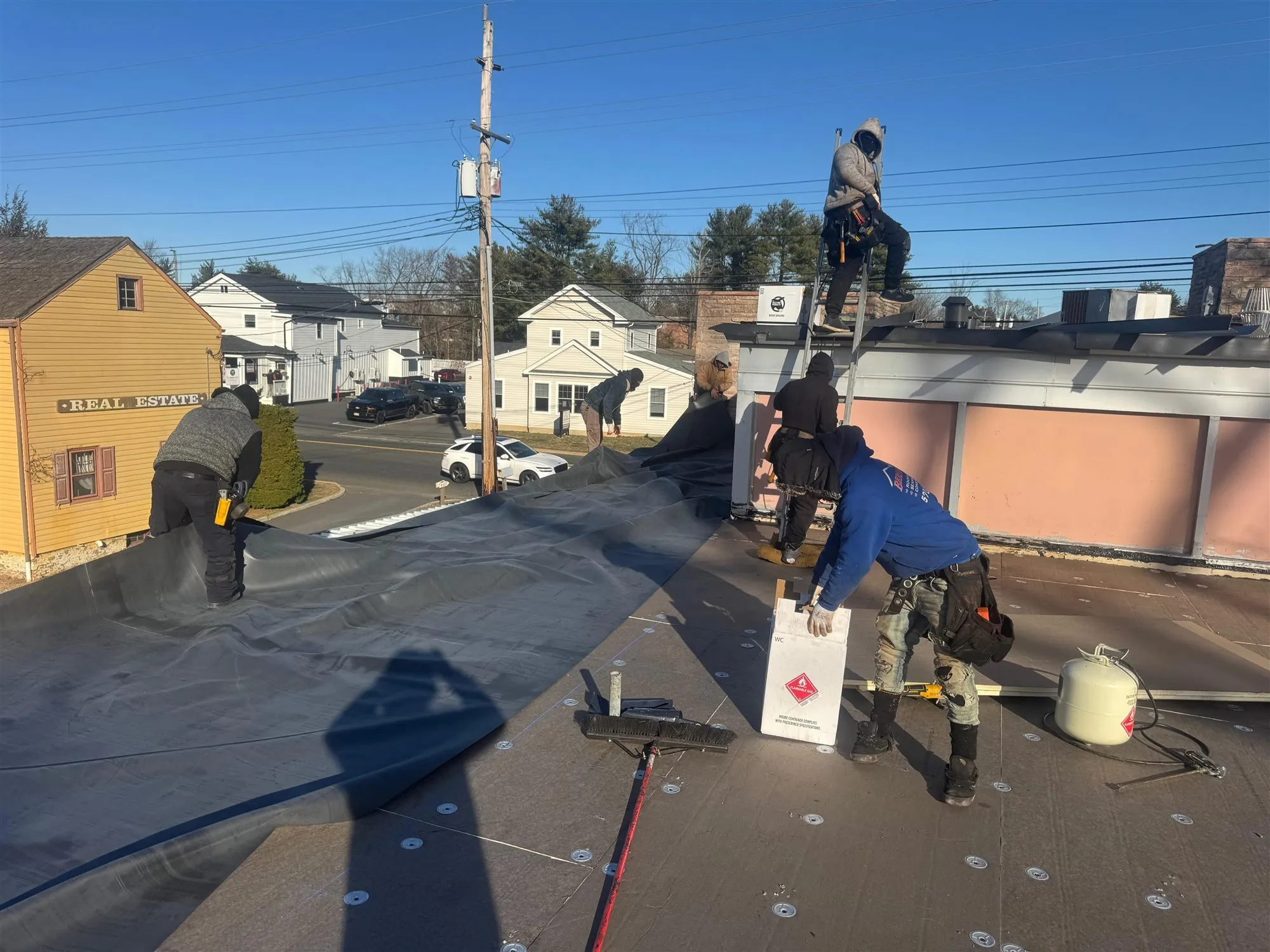 Imperial crew carrying roofing membrane up to a flat roof