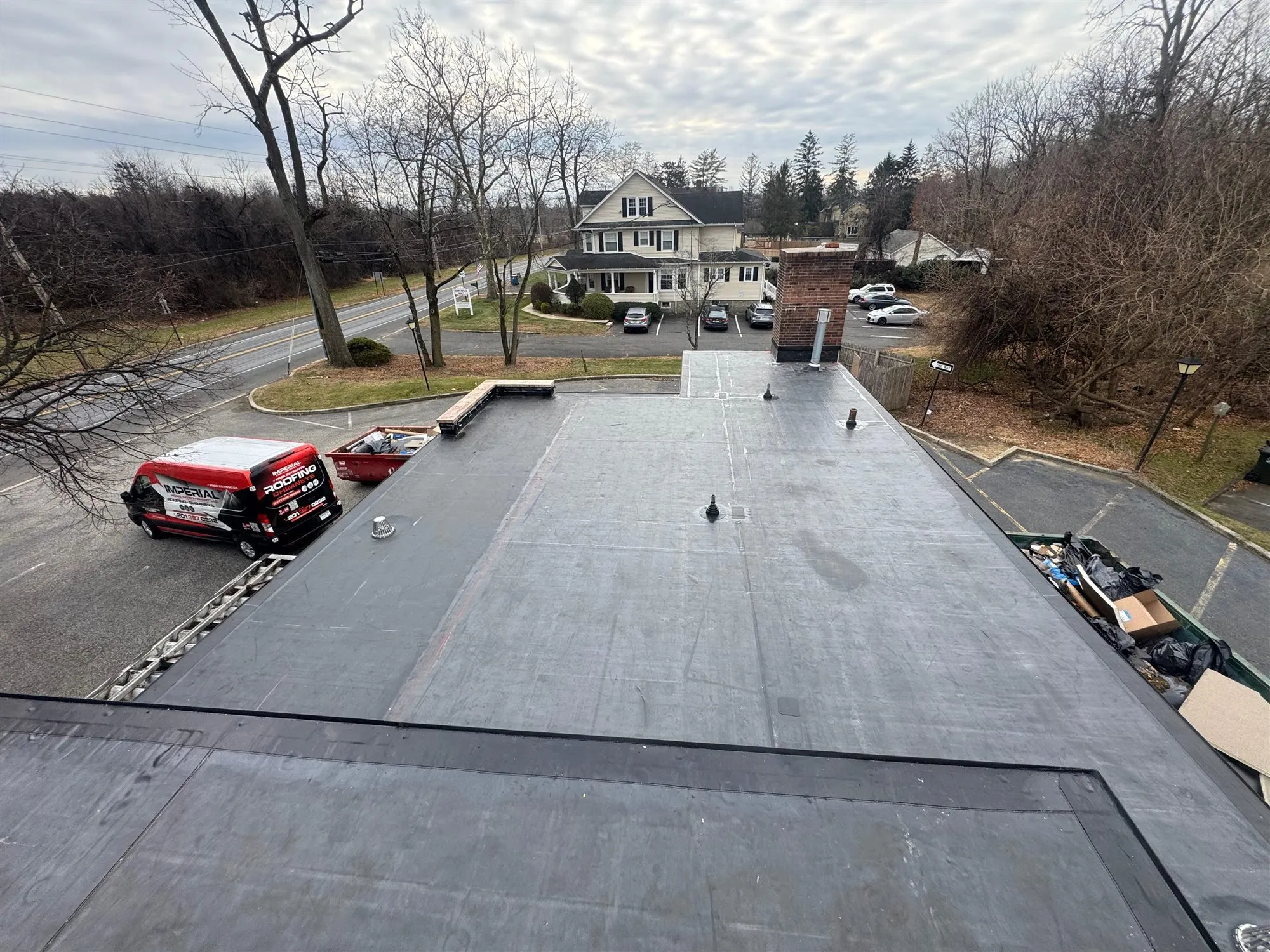 Finished black flat roof on a warehouse with the Imperial truck parked below